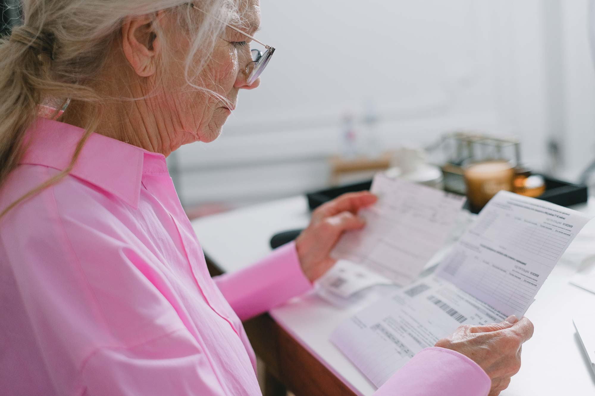 An older person reviews heating bills and financial paperwork during winter.